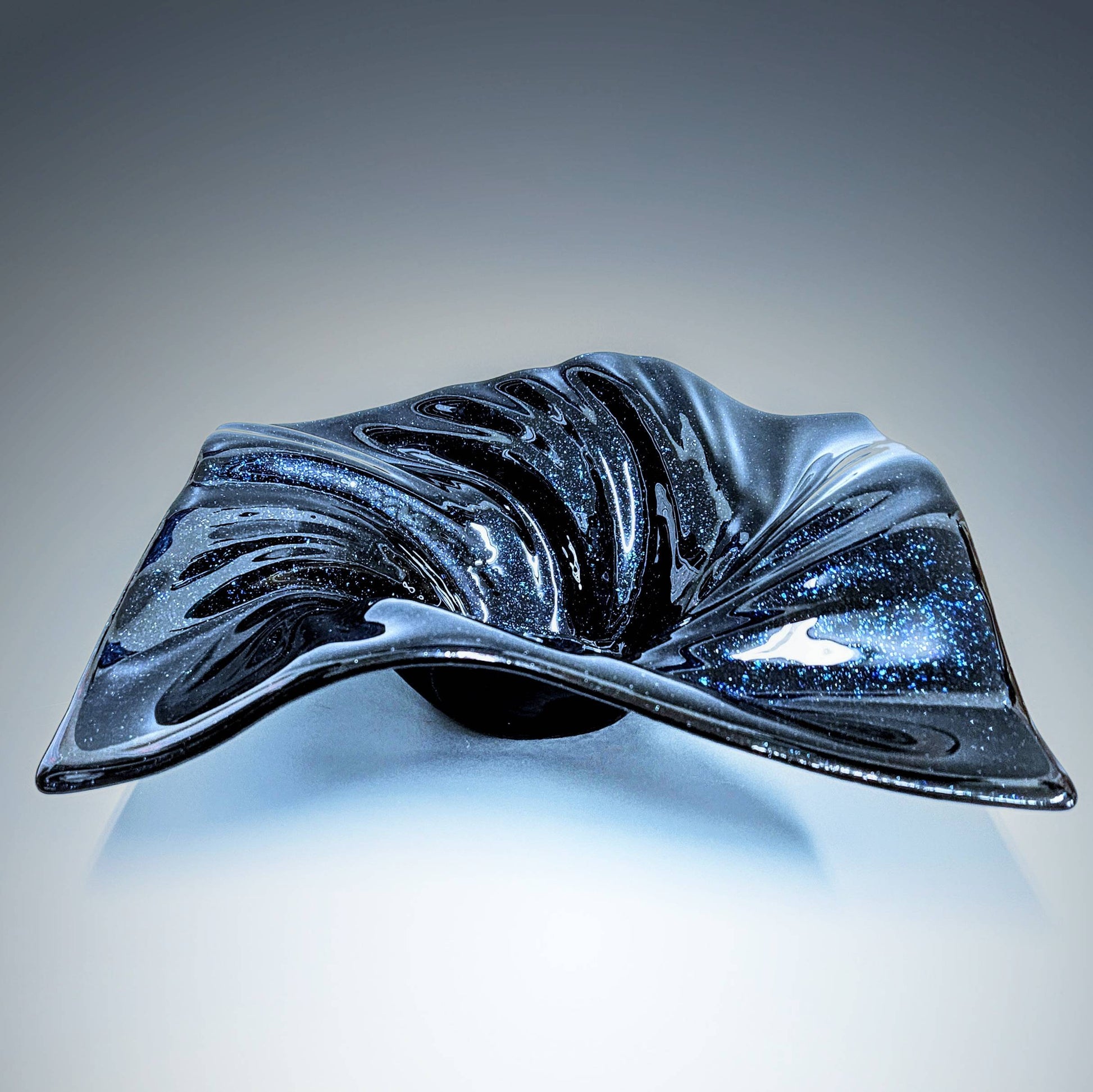 This stunning midnight blue aventurine fused glass bowl was handcrafted in the heart of Cincinnati, Ohio. The deep, velvety hue of midnight blue dances gracefully across the smooth surface of the bowl, evoking a sense of mystery and elegance.