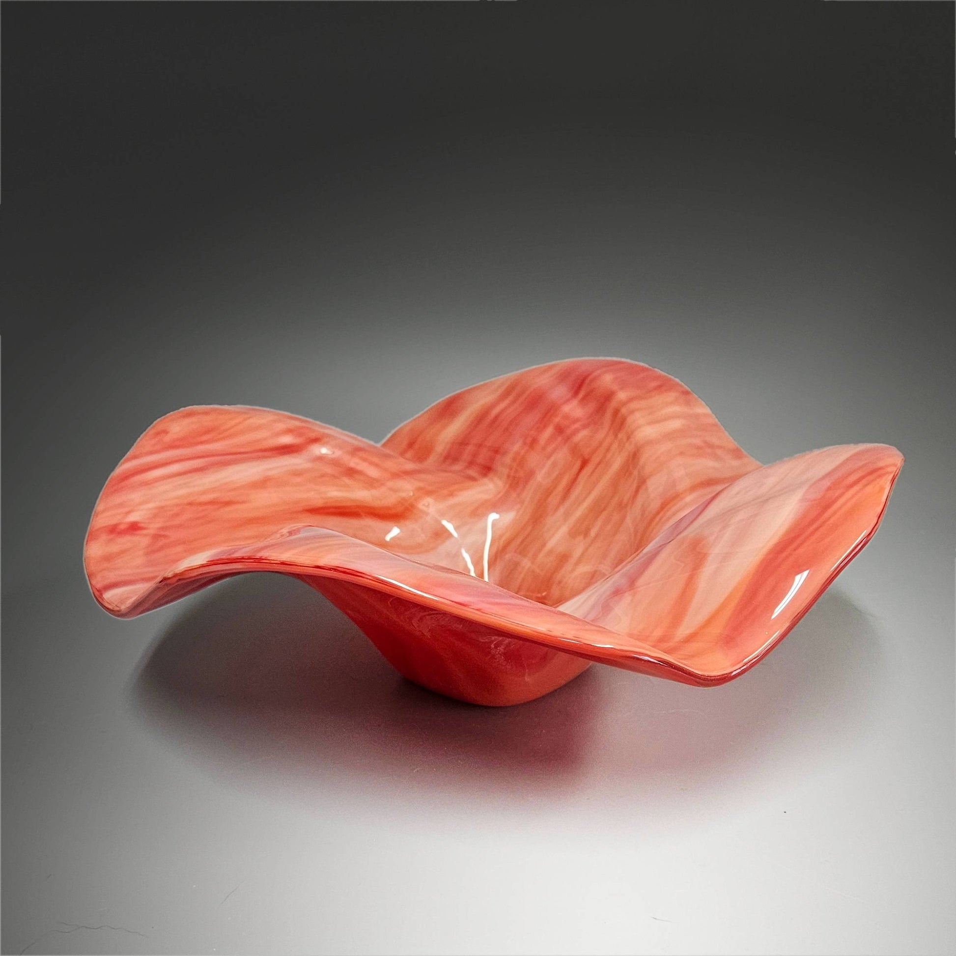 This mesmerizing glass art bowl captivates with its dynamic flow and vivid shades of reds and oranges. It’s a stunning conversation piece that seamlessly fits into any home décor. Whether displayed on a coffee table or side table, this bowl is sure to draw attention.