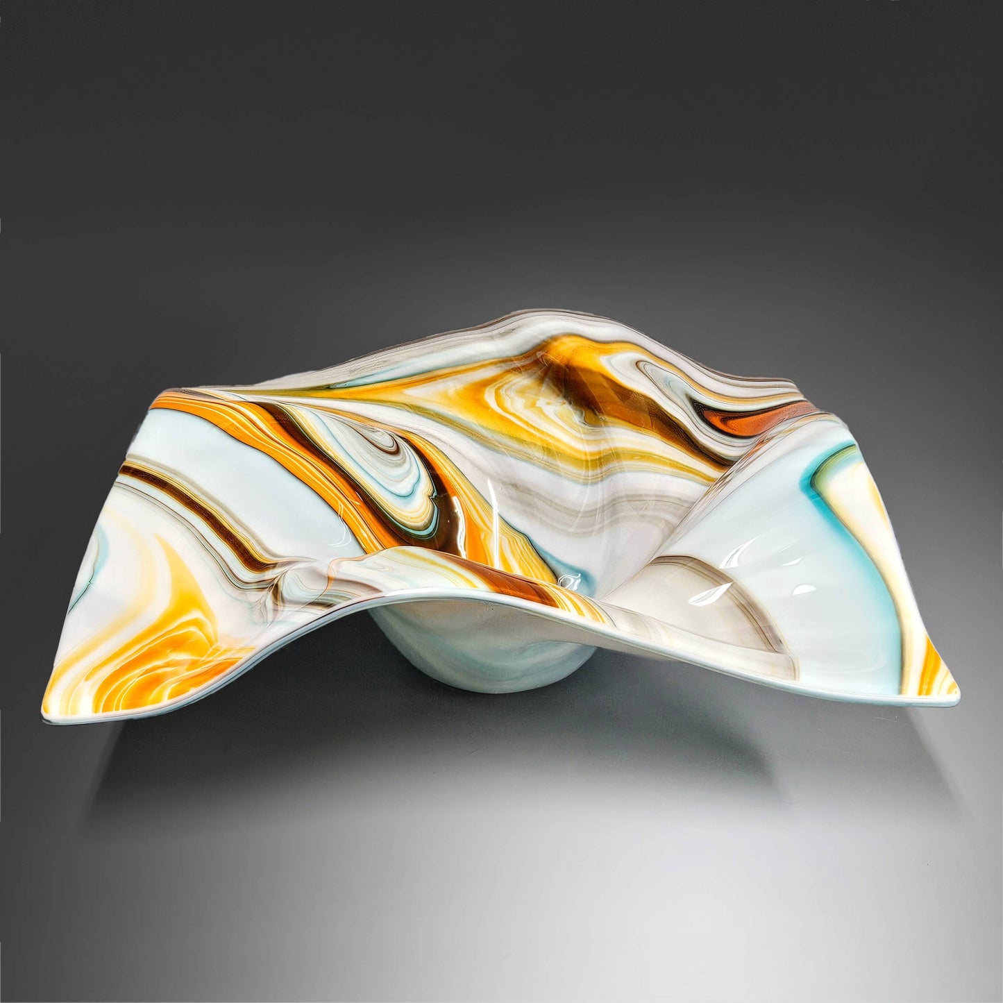 This mesmerizing, glass art bowl just flows with movement. Done in the most beautiful, mix of southwestern colors, including turquoise blue, orange, brown and ivory, it will garner many a conversation. This bowl would fit into just about any home décor