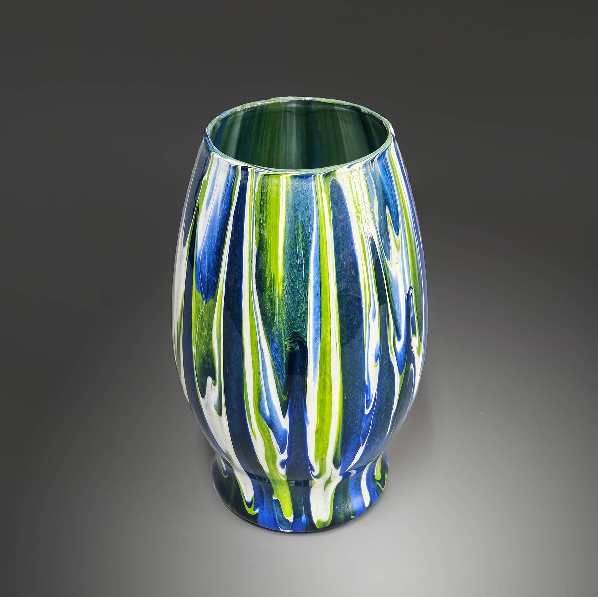 Elevate any space with this stunning Blue, Green, and White Painted Glass Flower Vase. This exquisite piece of art seamlessly blends vibrant colors in a fluid, dripping design, creating a captivating visual effect that is sure to impress.