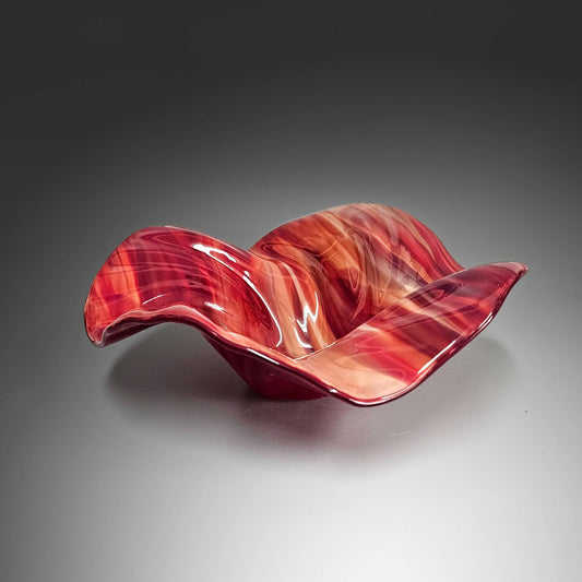 This beautiful glass wave bowl is done in striking mix of shaded reds.  It's done in a mix of transparent glass which lets the light play off the swirls in the glass beautifully. The color is stunning.