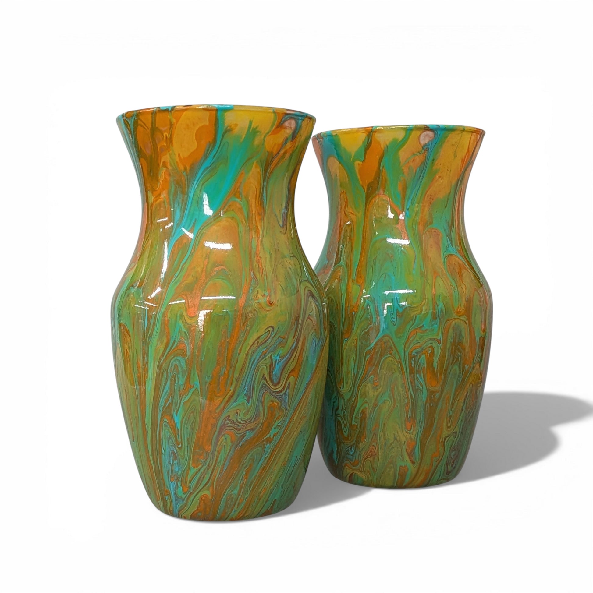 Two marbled glass vases in green and orange on a white background