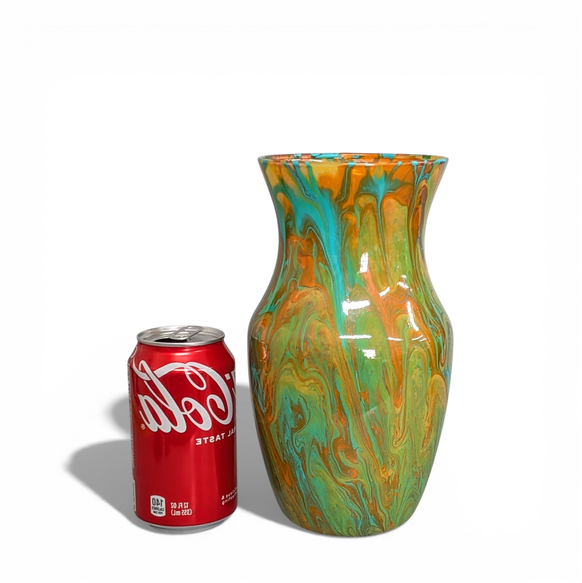 Colorful marbled vase next to a Coca-Cola can on a white background
