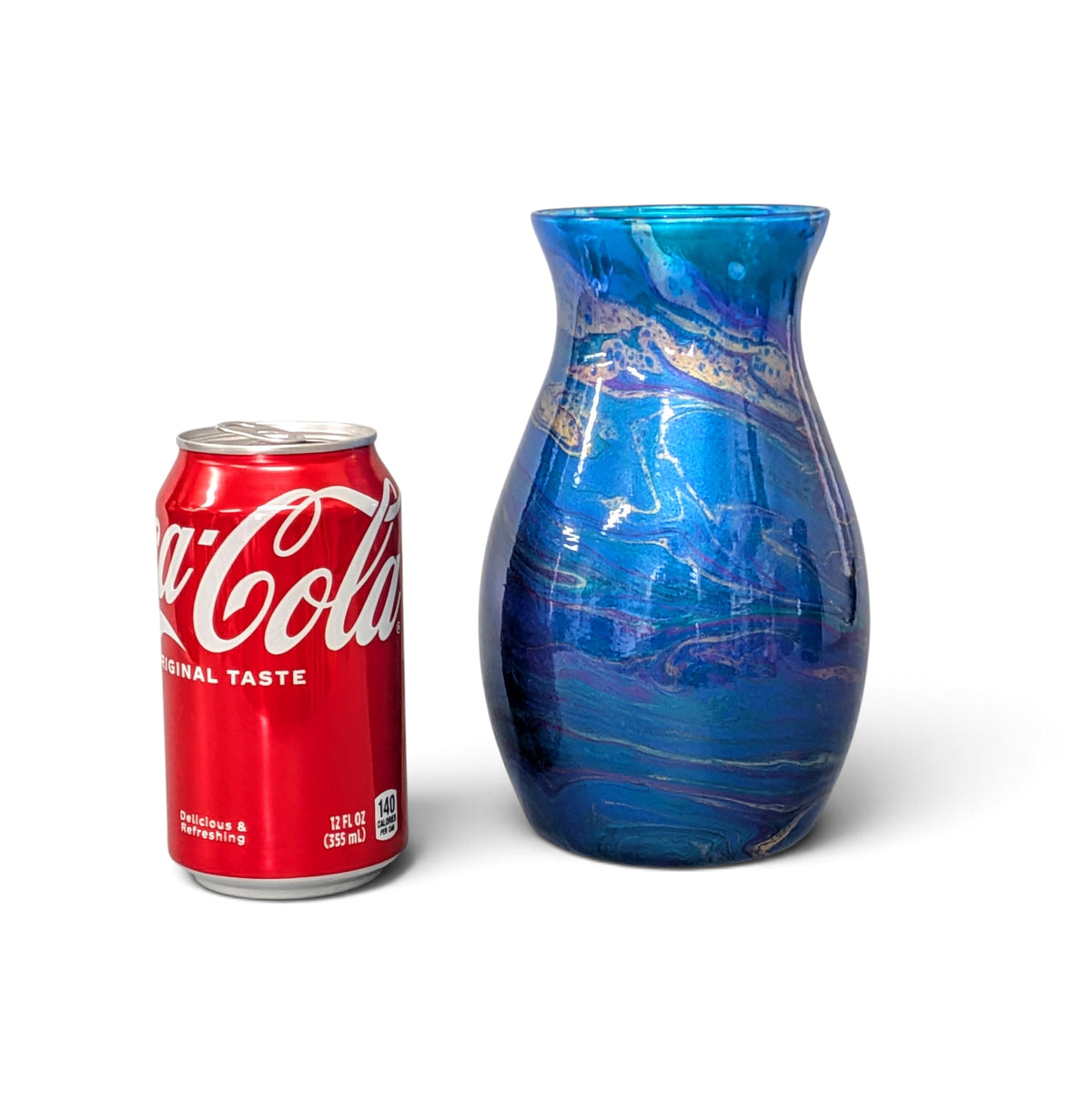 A blue and purple marbled glass vase shown next to a red Coca-Cola can for scale, on a clean white background.